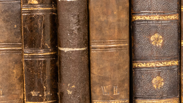 Row of old 100 years old books on a shelf.