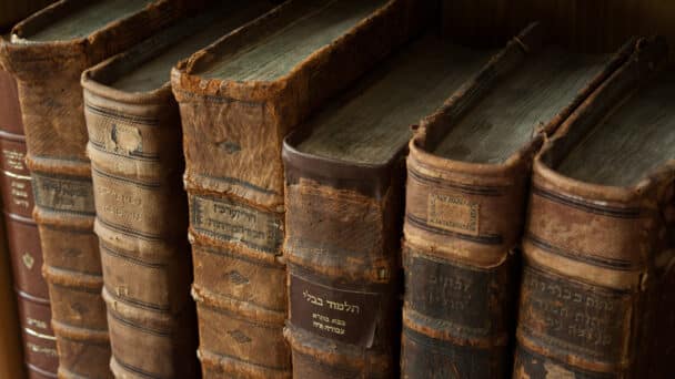 Dusty, worn and faded leather-bound Jewish holy books stacked