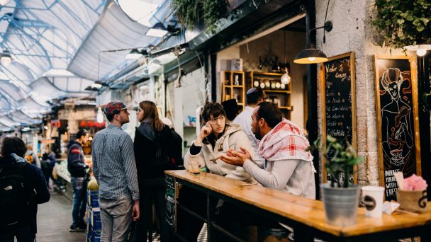 people gathered outside a coffee bar in the shuk