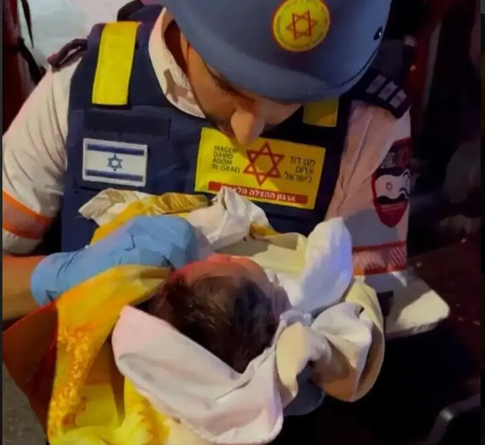 An emergency worker tends to a baby found in a damaged home